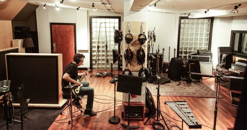 artist playing guitar in a recording studio
